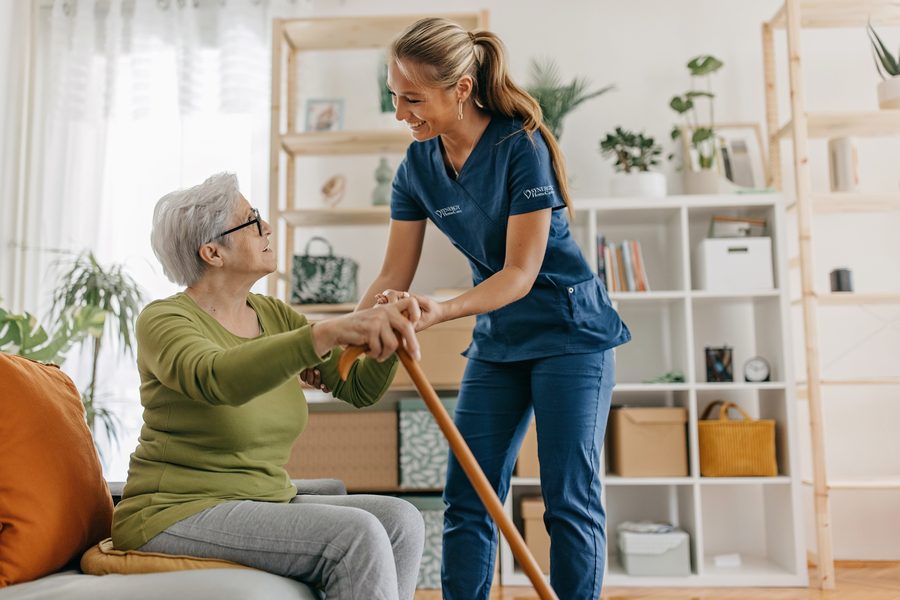 A SYNERGY HomeCare caregiver helping a client stand safely